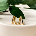 A pair of gold hoop earrings with black beading.