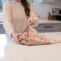 Person holding a floral-patterned fabric bag in a kitchen setting