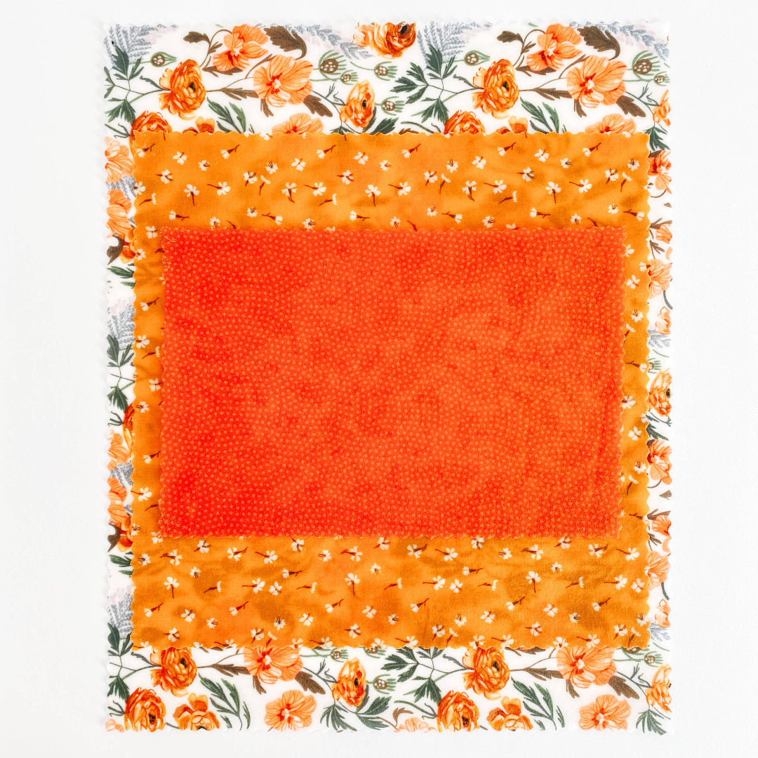Floral-patterned fabric with a bright orange square in the center on a white background