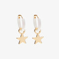 Pair of gold star earrings with white rubber bands on a light beige background