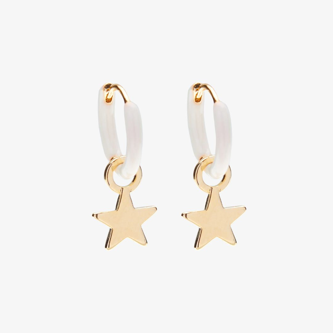 Pair of gold star earrings with white rubber bands on a light beige background