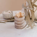 Stack of stone-like containers with a toothpick holder on a neutral background