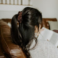 Person sitting on a brown leather couch reading a book with a neutral background