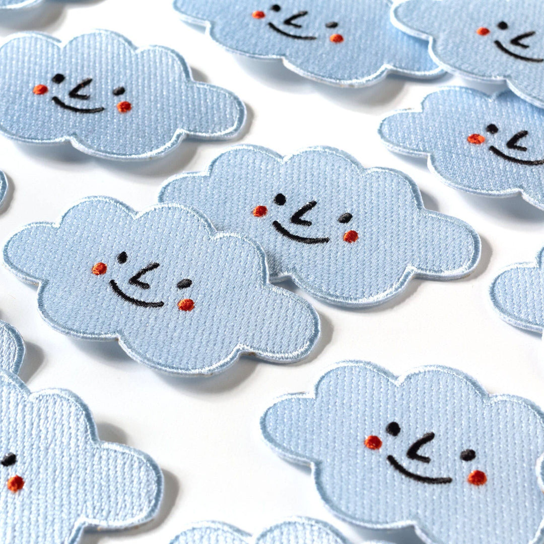 Collection of cloud-shaped patches with smiley faces on a white background