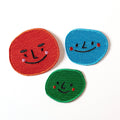 Three colorful smiley face patches on a white background