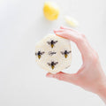 Hand holding a round white object with bee illustrations and 'Globitos' branding on a light background.