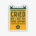 A rectangular banner-shaped sticker with a bold black outline and a golden yellow background. The text "CRIED" is prominently displayed in large dark teal letters, followed by "BUT I DID THE THING ANYWAY" in smaller dark teal text. A single dark teal teardrop icon is at the bottom.