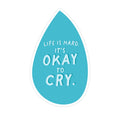 Blue teardrop-shaped sticker with white text 'Life is hard. It's okay to cry.' on a white background