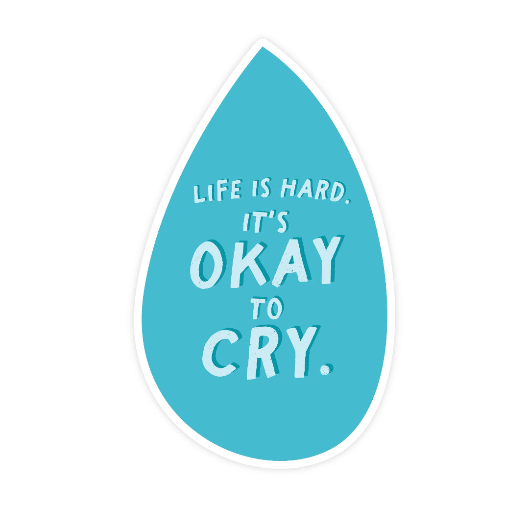 Blue teardrop-shaped sticker with white text 'Life is hard. It's okay to cry.' on a white background