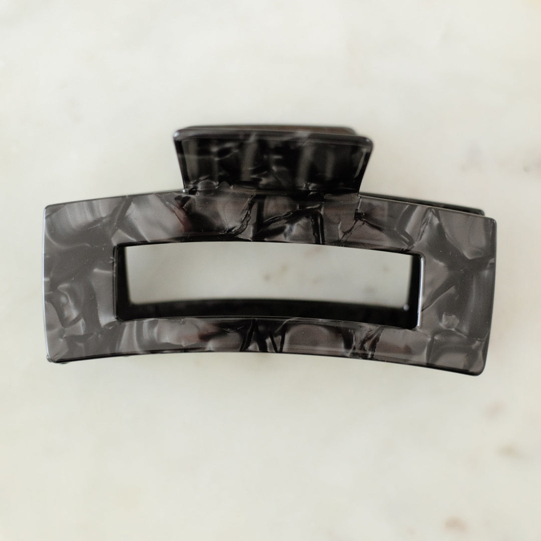 Black hair clip on a white marble surface