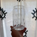 Clear glass with heart patterns held in front of a decorative background