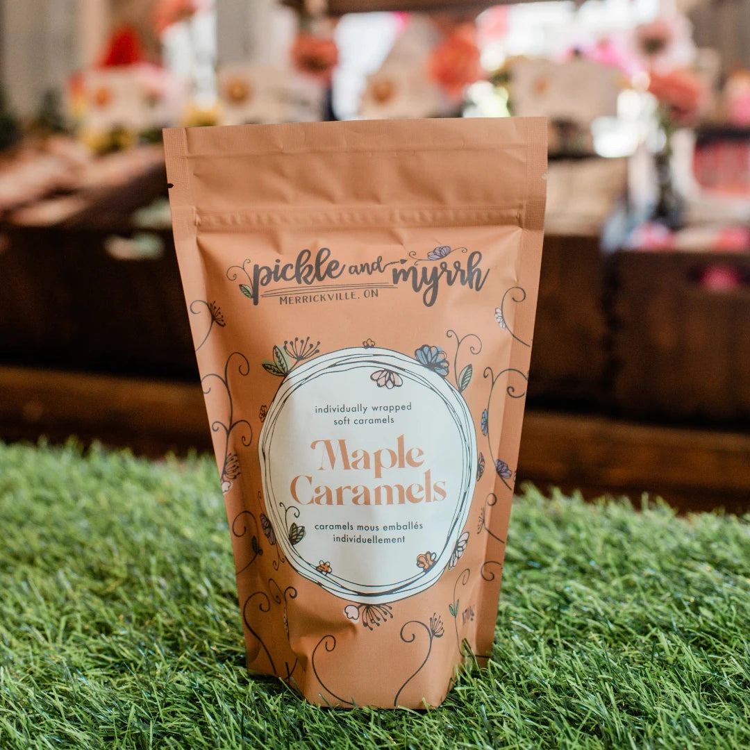 A brown paper bag filled with maple caramels. The bag has a label that says "Pickle & Myrrh" and "Maple Caramels."