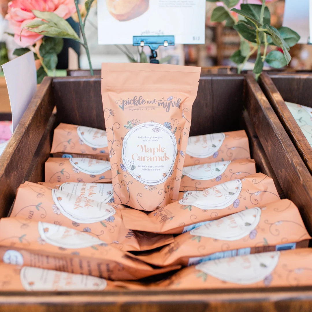 A brown paper bag filled with maple caramels. The bag has a label that says "Pickle & Myrrh" and "Maple Caramels."
