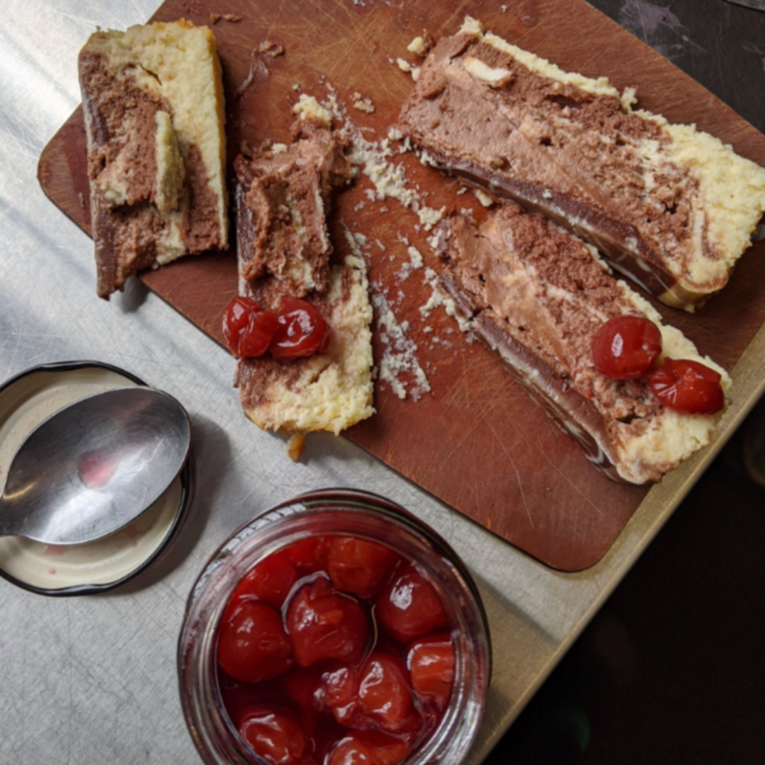 A jar of Maraschino Cherries from Top Shelf Preserves. The jar is filled with red cherries and has a black label with white text. The label includes the product name, "Product of Canada," and instructions to keep refrigerated after opening.