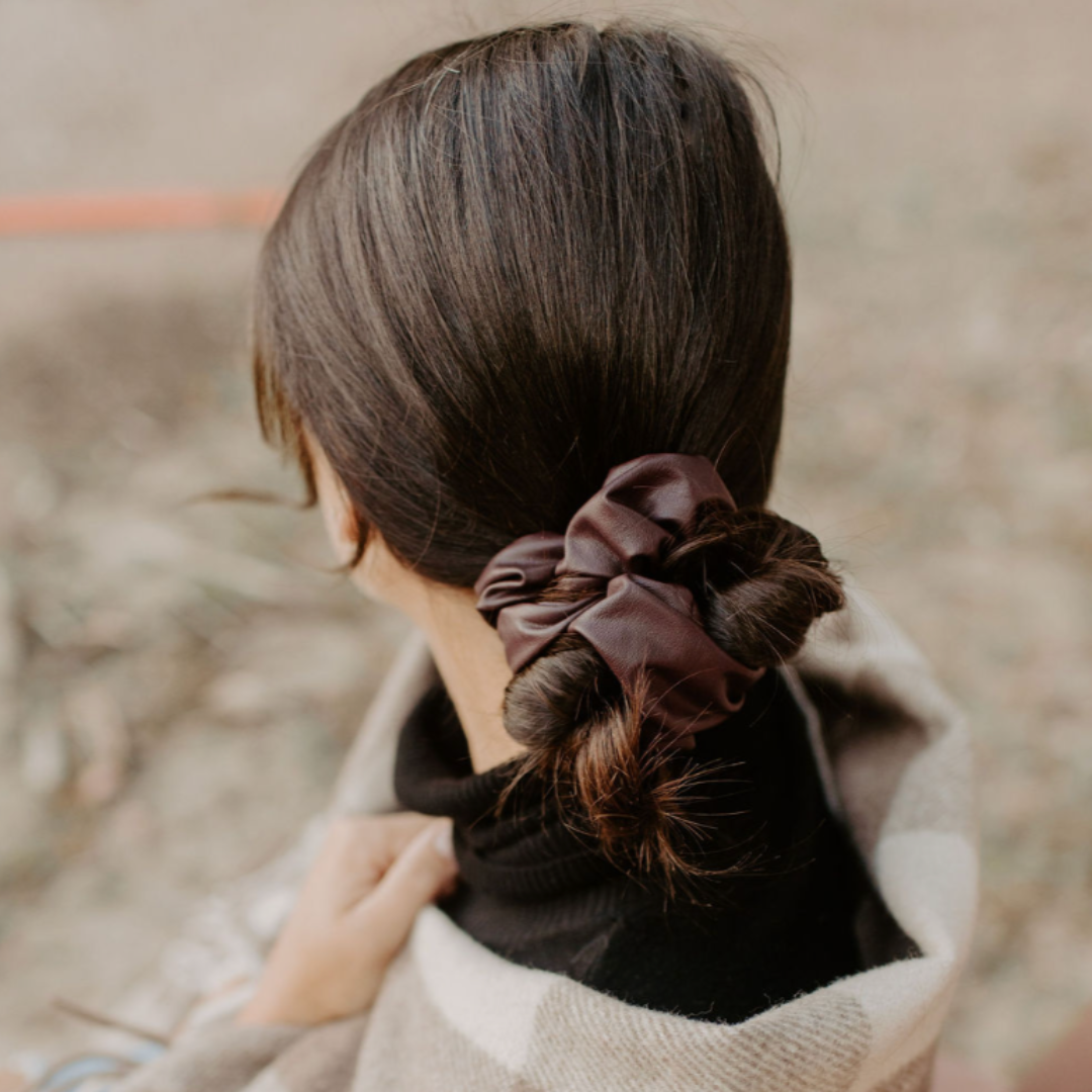 Person with a brown scrunchie in their hair, wrapped in a checkered blanket.