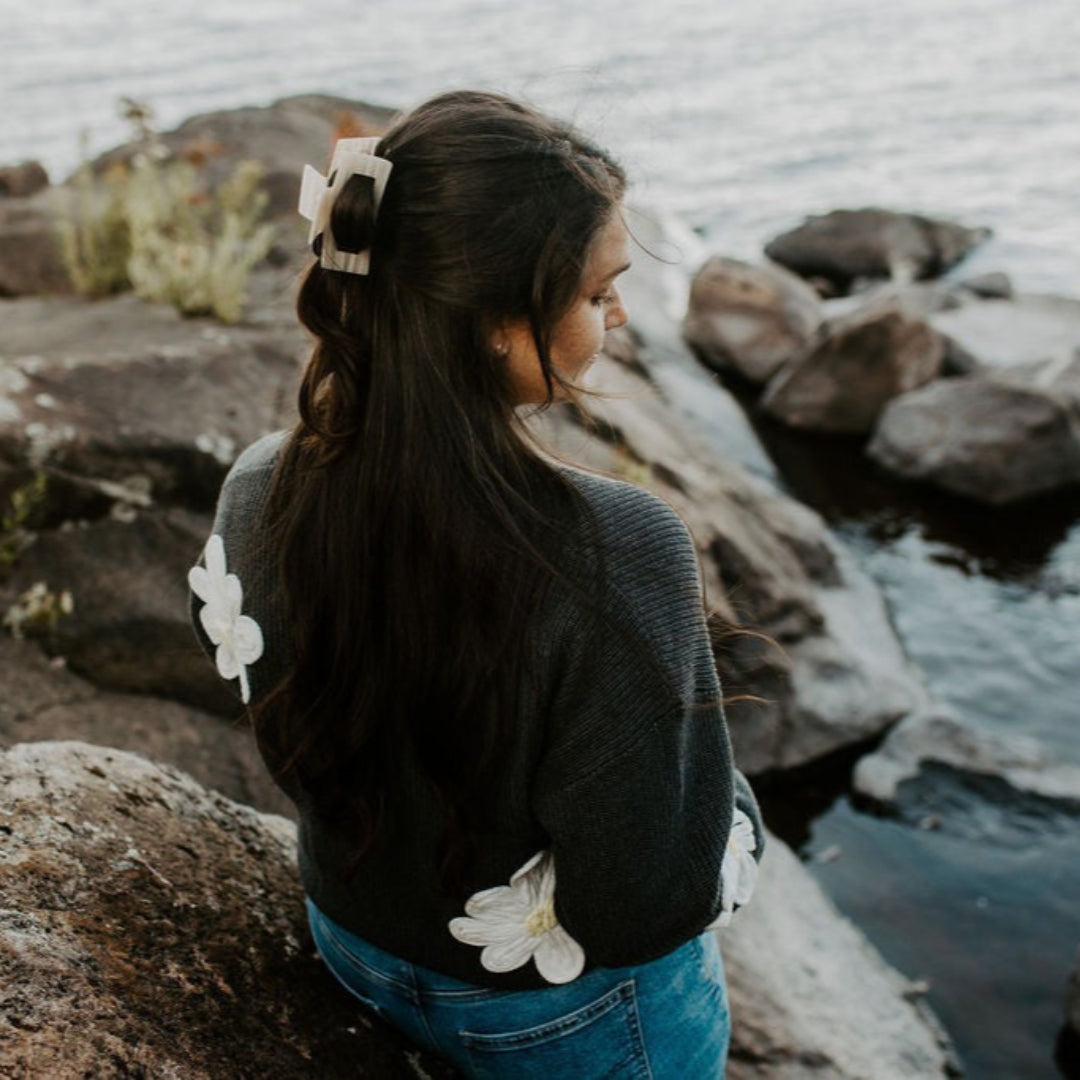 Woman with floral hair accessories standing by a rocky waterfront