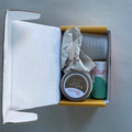 Open box containing a small jar and a can on a gray background