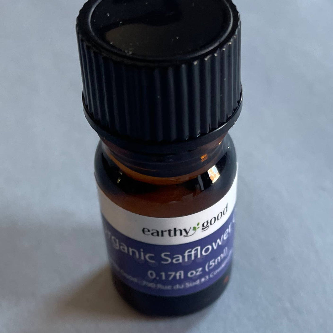 Small bottle of organic safflower oil with a black cap on a light gray background