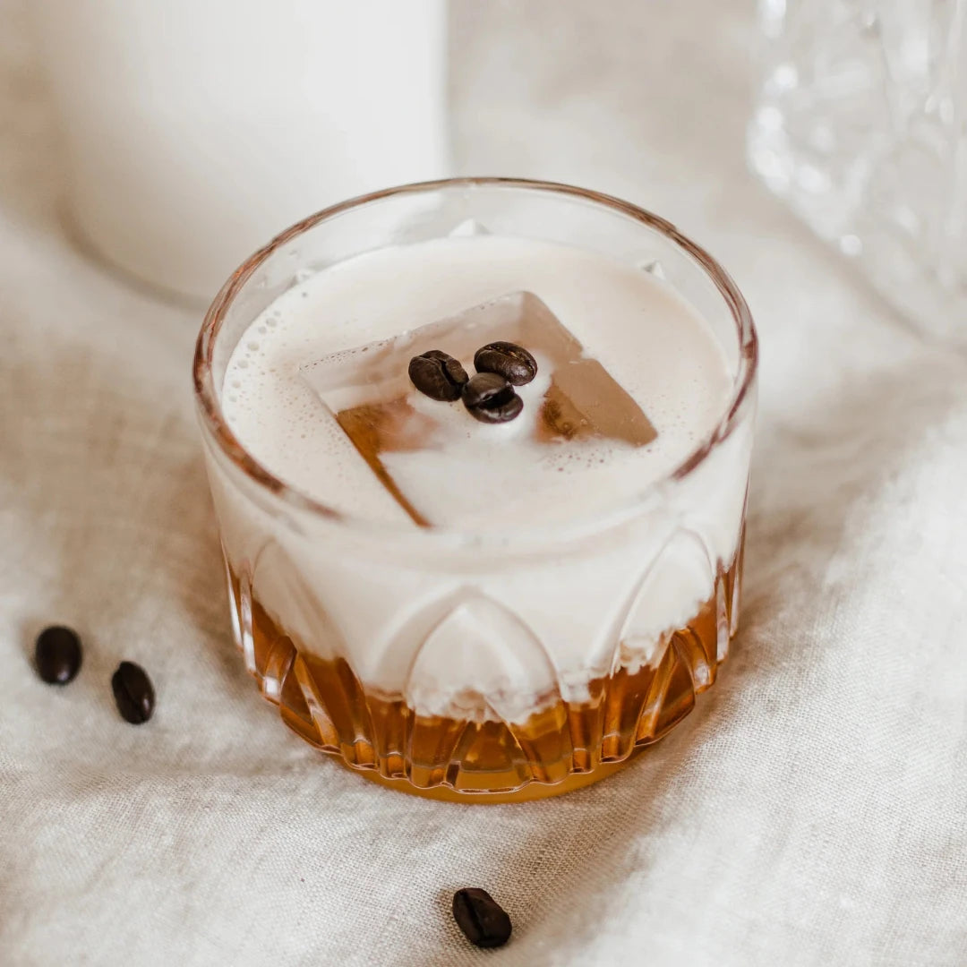 A glass jar filled with dried orange slices, cocoa nibs, and other ingredients. The jar has a white label with the Maiden Voyage logo and the product name "Mocha Old Fashioned Cocktail Infusion."