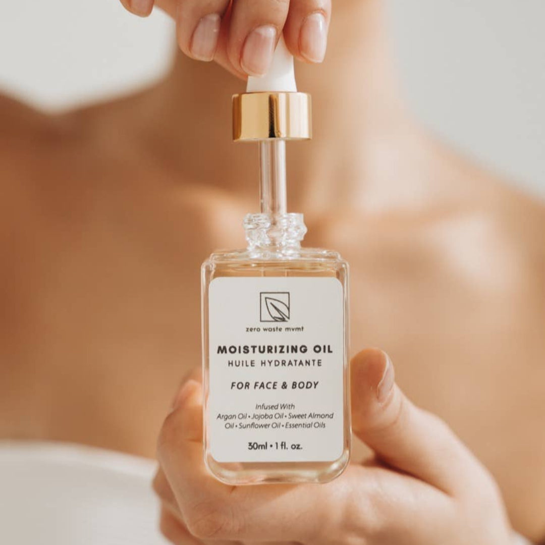 Hand holding a bottle of moisturizing oil with a blurred background