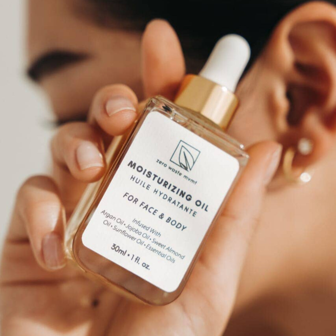 Hand holding a bottle of moisturizing oil with a blurred background