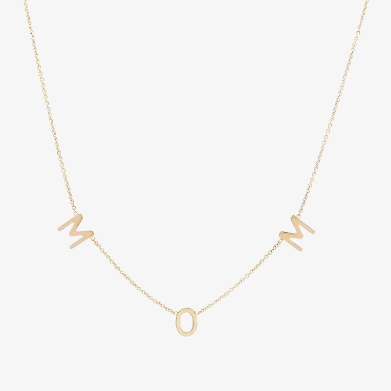 A delicate gold-filled necklace spelling out 'MOM' with individual letter charms evenly spaced along a fine chain, displayed on a white background. This heartfelt necklace is available in Ottawa, Ontario, Canada.