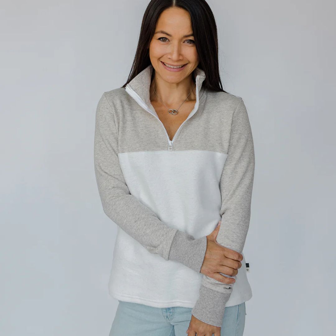 Woman wearing a gray and white pullover against a plain background