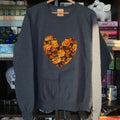 Gray sweatshirt with a floral heart design on a hanger against a bookshelf background