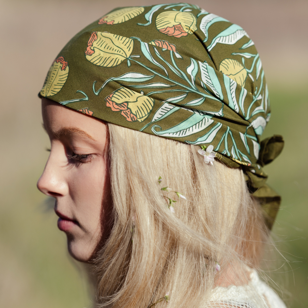Person wearing a green patterned headscarf with a blurred natural background