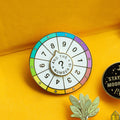 A circular pin with a colorful wheel featuring numbers from 0 to 9. The phrase "And the Numbers" is written in the center.