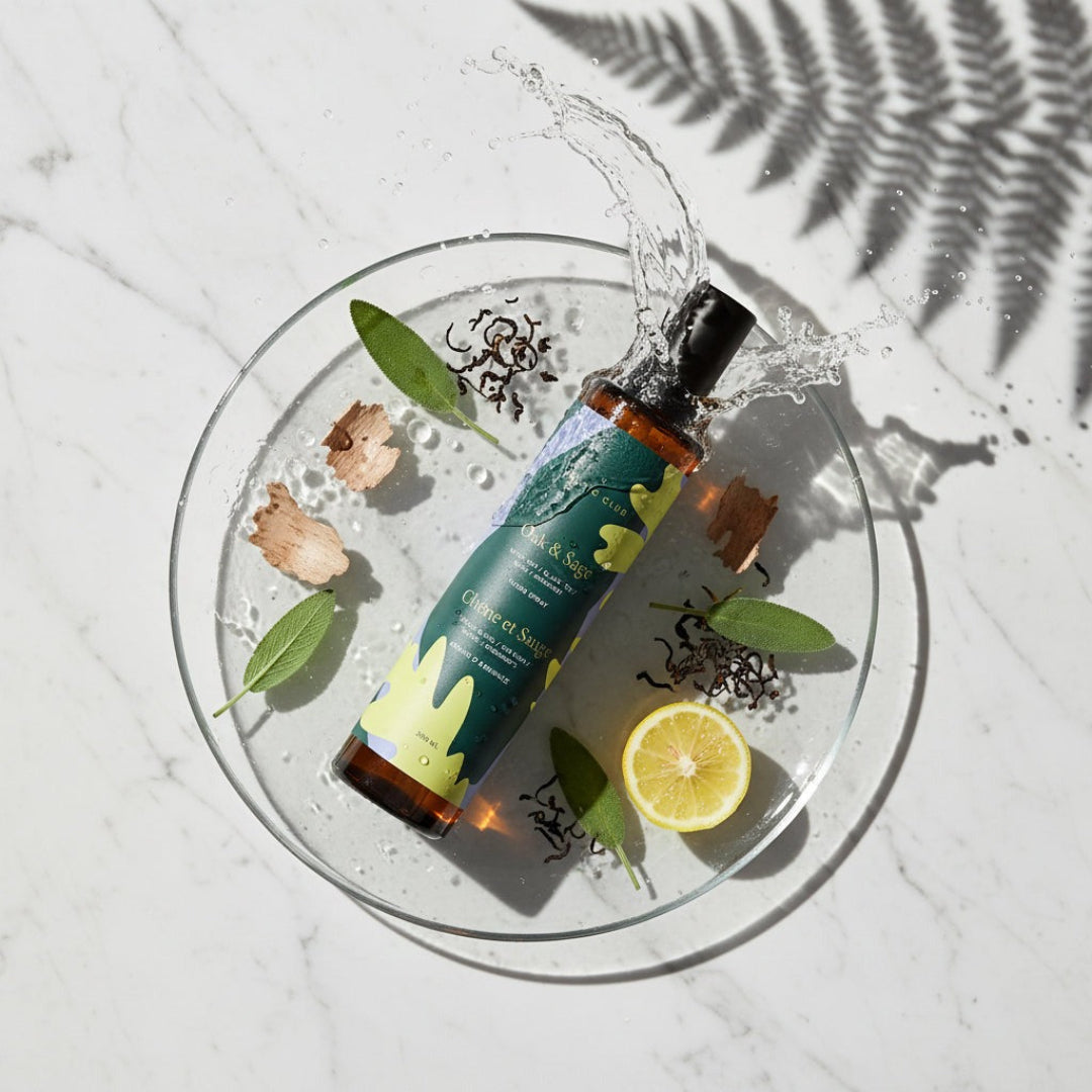 Bottle of natural product with leaves and lemon on a white surface