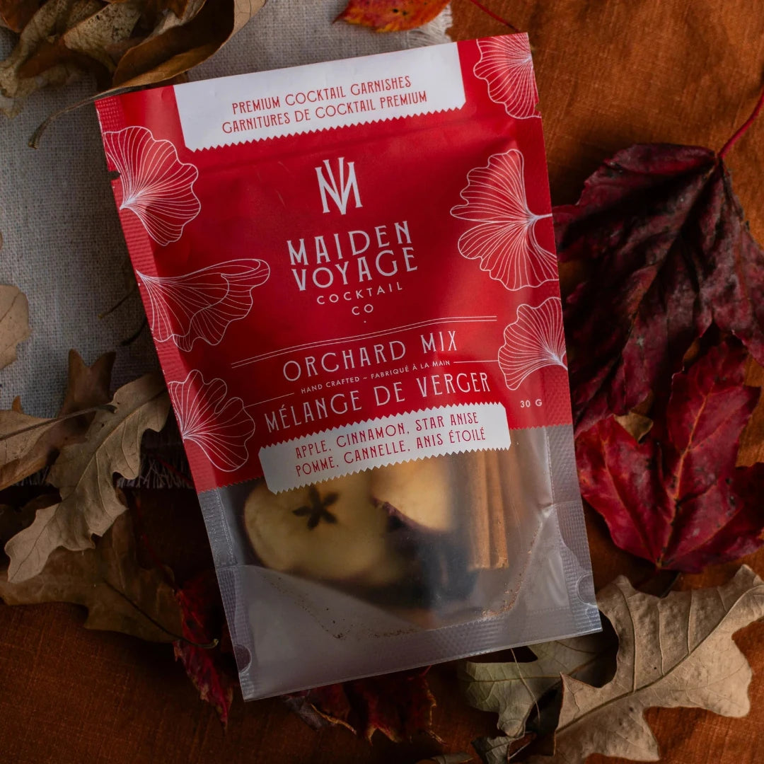 A clear plastic pouch containing a Maiden Voyage Orchard Mix. The pouch has a red background with a white label featuring the Maiden Voyage logo and the product name. The label also lists the ingredients: Apple, Cinnamon, Star Anise.