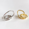 A set of silver and gold-plated geometric open statement twist rings, featuring unique, flowing designs, displayed side-by-side on a light-colored surface. These are modern and bold rings, available in Ottawa, Ontario, Canada.