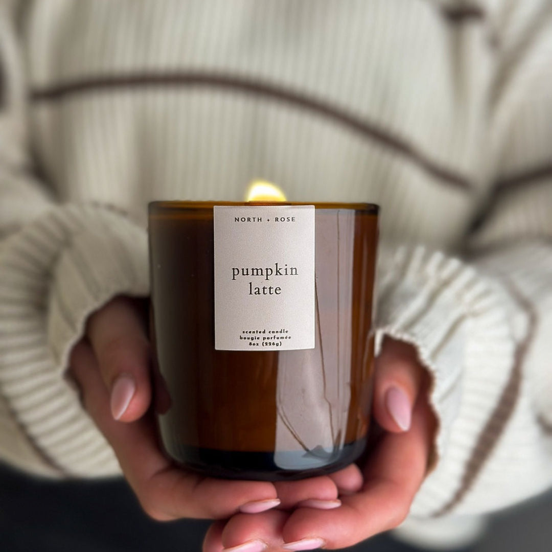 Person holding a 'pumpkin latte' scented candle with a label.