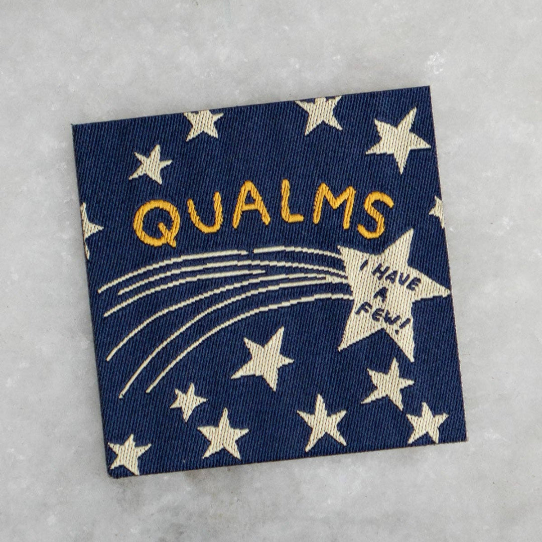 Patch with 'QUALMS' text and star design on a textured surface
