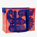 A reusable shoulder tote bag with a vibrant and colorful design. The bag is made from recycled materials and features a large, folk-art style bird surrounded by flowers and plants. The bird is primarily blue with red accents, while the flowers are in shades of pink, orange, and yellow. The bag has sturdy blue handles.