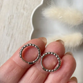 A pair of 925 sterling silver ball hoop earrings, featuring a beaded design, displayed on a white textured surface with white floral accents. The earrings are dainty and high-quality, available in Ottawa, Ontario, Canada.