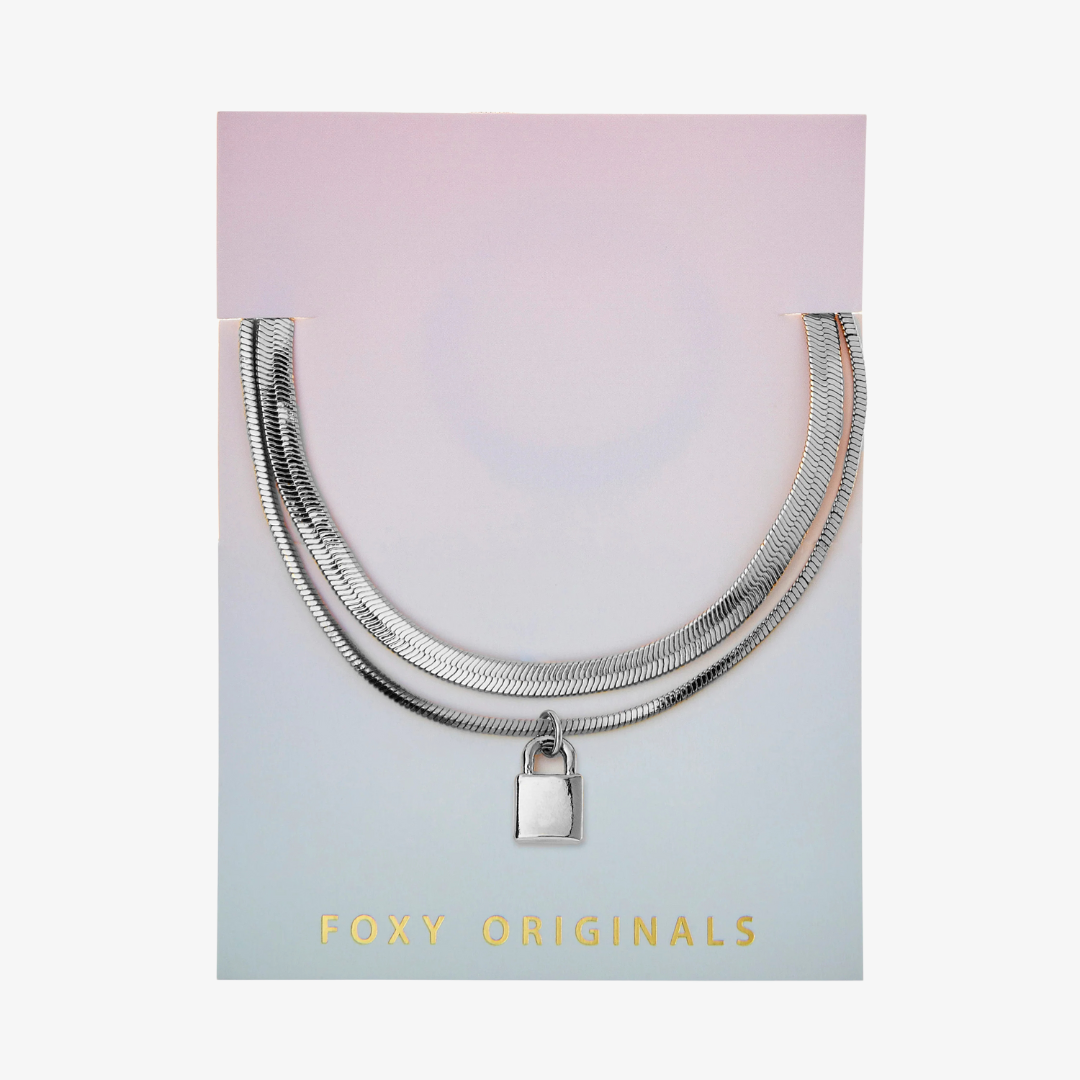A silver layered bracelet with a small padlock charm. The bracelet has two chains of different widths, and the padlock charm hangs from the thinner chain.
