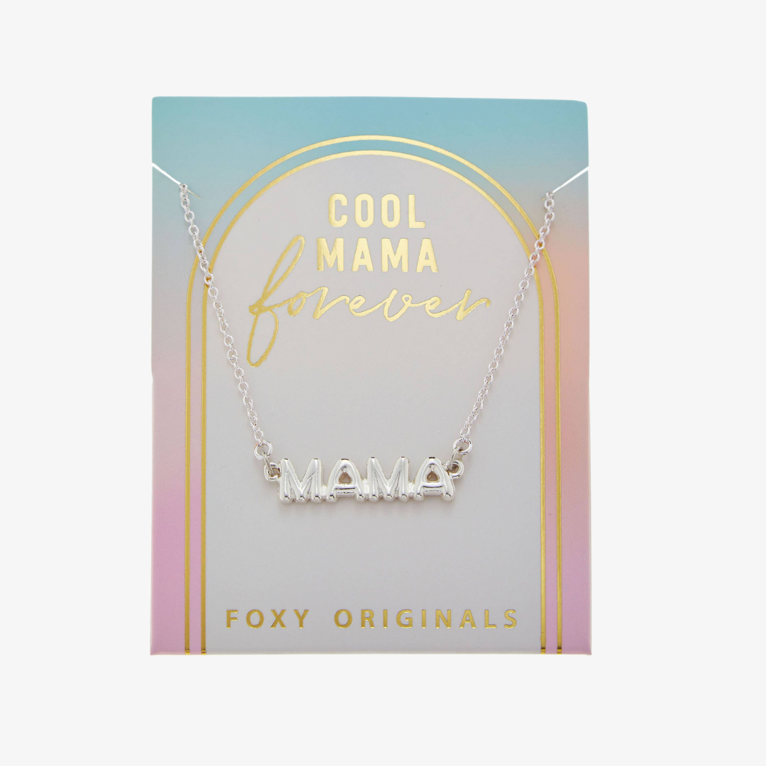 A silver necklace on a pink background. The necklace features a silver pendant with the word "MAMA" in bold letters. The text "COOL MAMA FOREVER" is printed on the background card, along with the brand name "Foxy Originals."