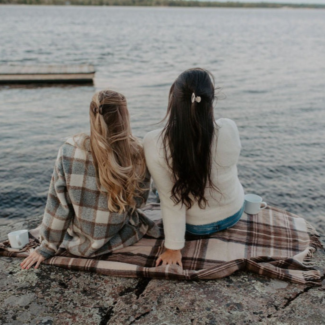 Two people sitting on a blanket by a lake