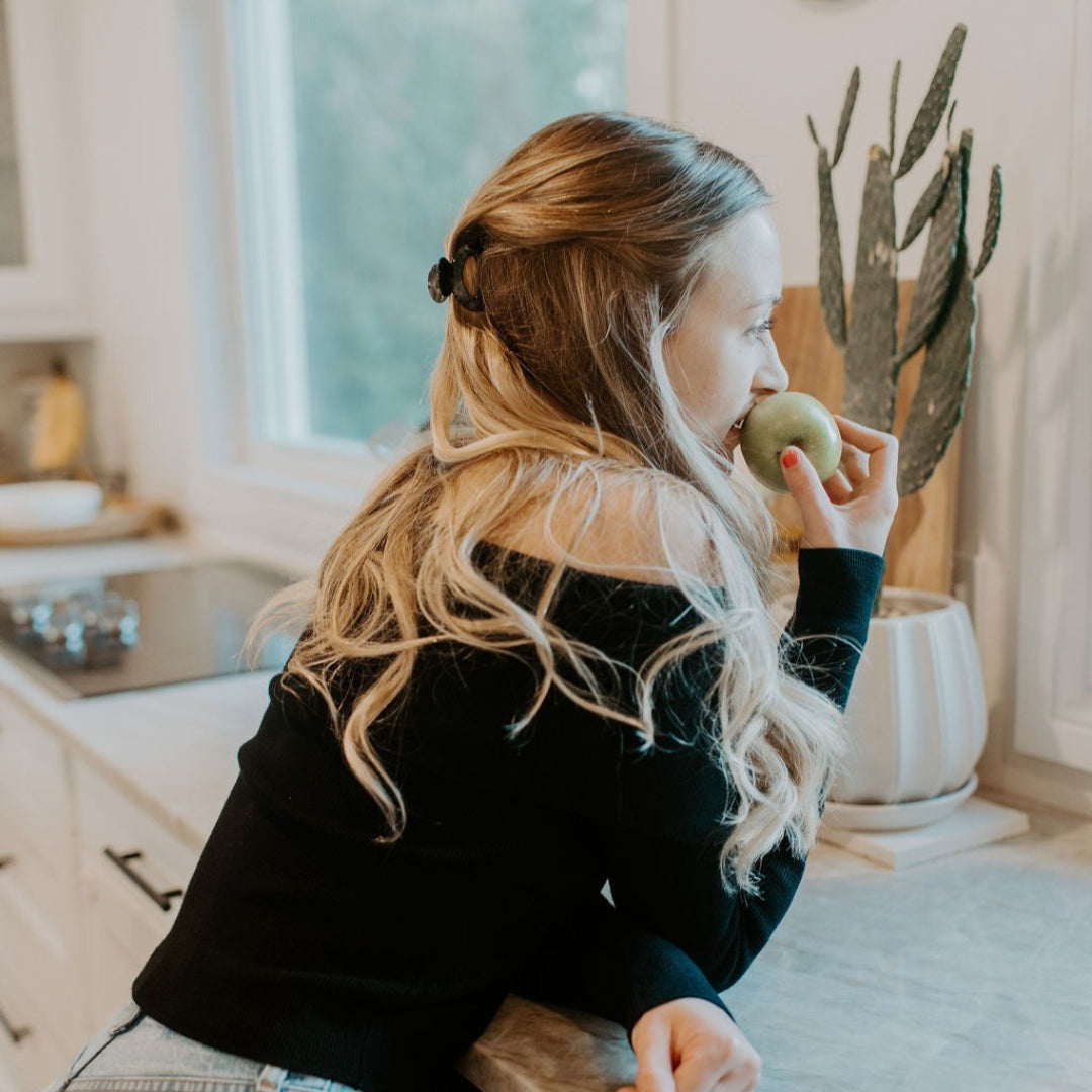 Woman eating an apple in a kitchen