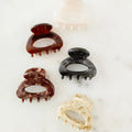 Three hair clips in brown, black, and beige on a light background