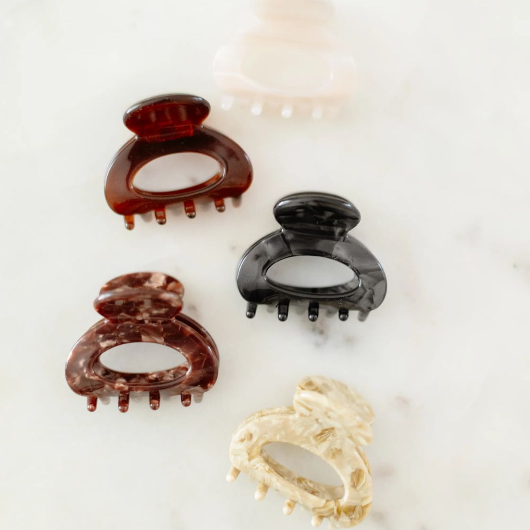 Three hair clips in brown, black, and beige on a light background