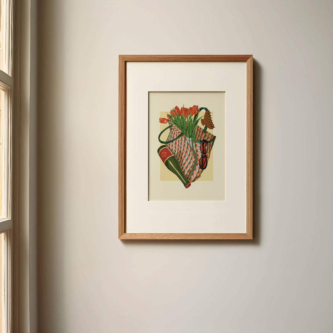 Framed artwork of a colorful still life with flowers and vegetables on a beige wall.