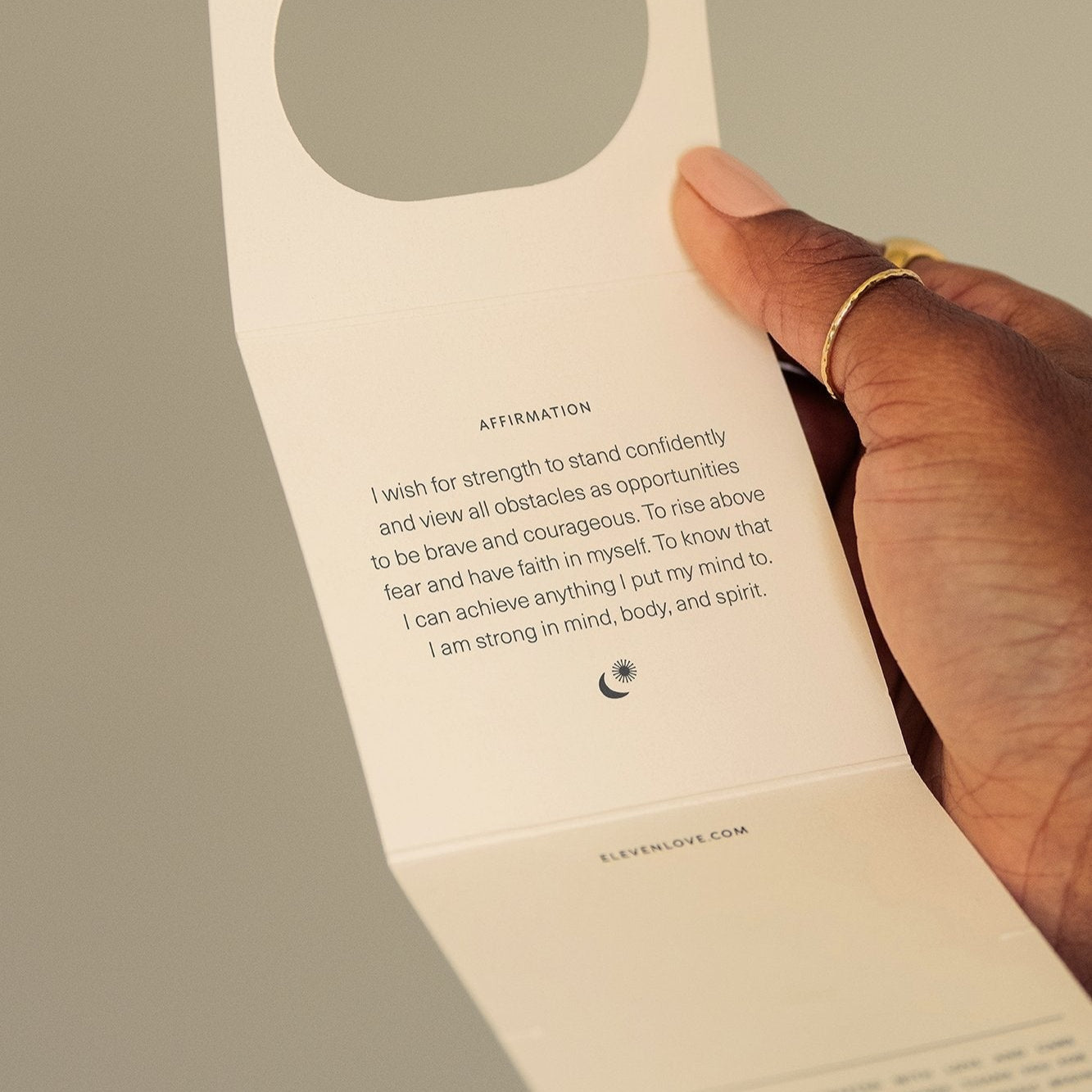 Hand holding a folded card with text and a circular cutout.