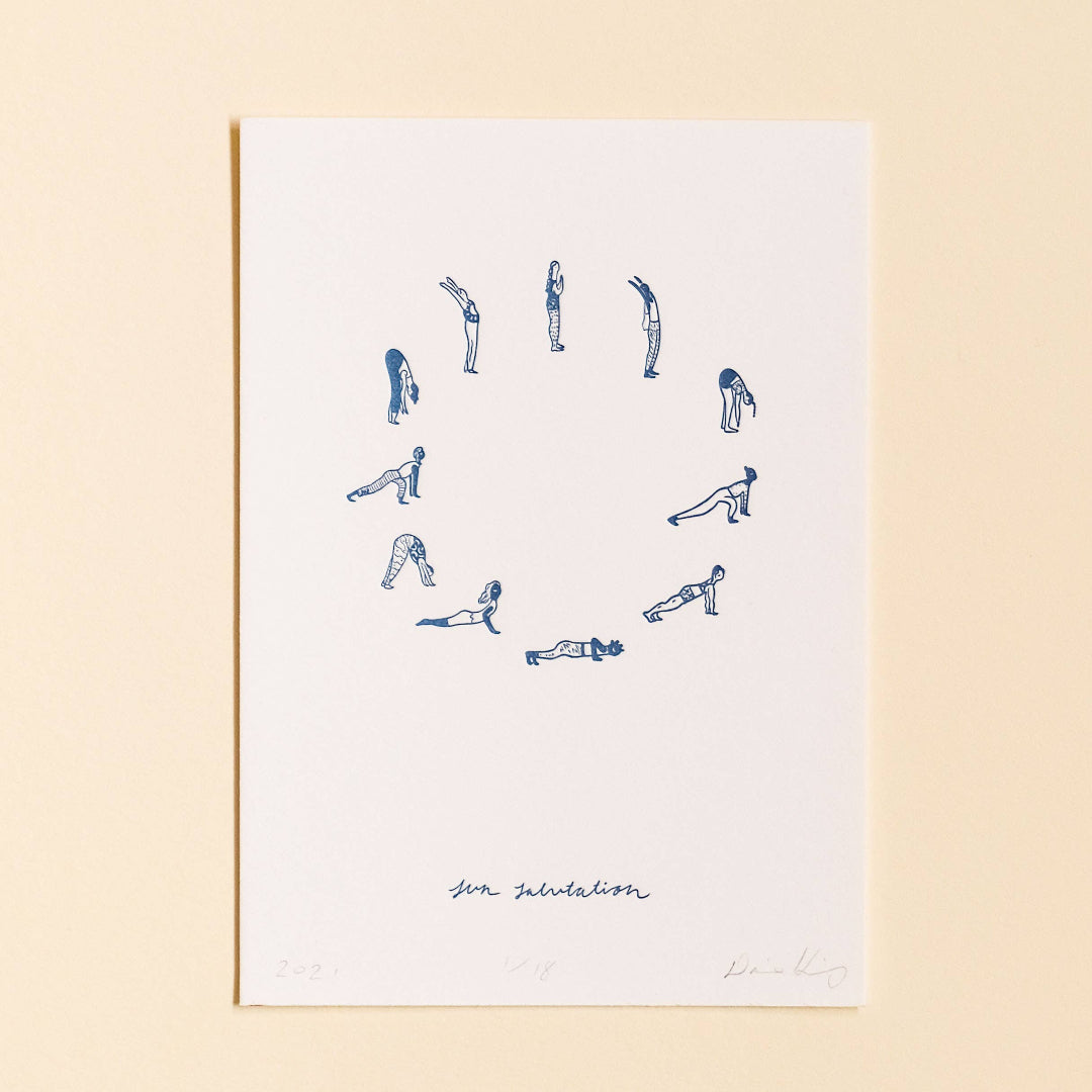 Framed artwork with blue line drawings of yoga poses on a white background