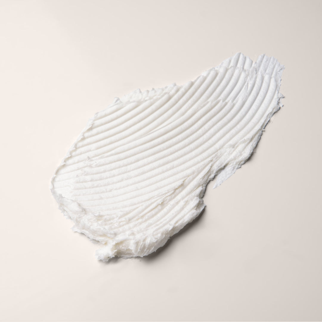 A small, open, silver metal tin of Everist's "The Fragrance-Free Body Wash Concentrate Travel Mini," revealing a white solid product inside. The tin's lid is propped against the base, and text on the side indicates it's dermatologist-developed and contains 20ml of product.