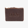 Bar of dark soap with 'aide' embossed on a white background