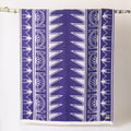Purple and white patterned towel hanging on a rack against a white background
