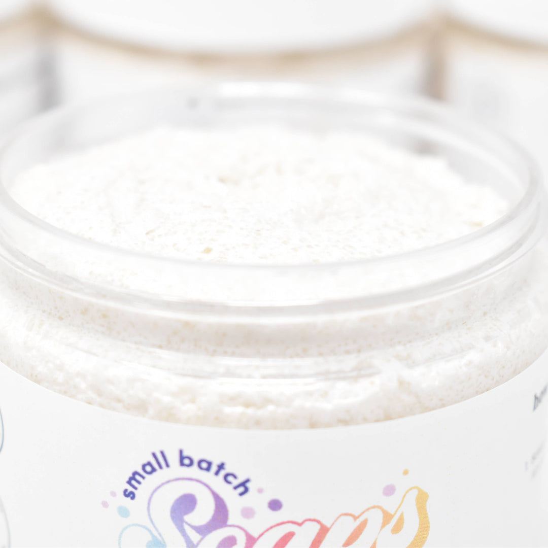 Jar of whipped cream with 'small batch' and 'Sara's' branding on a light wooden surface.